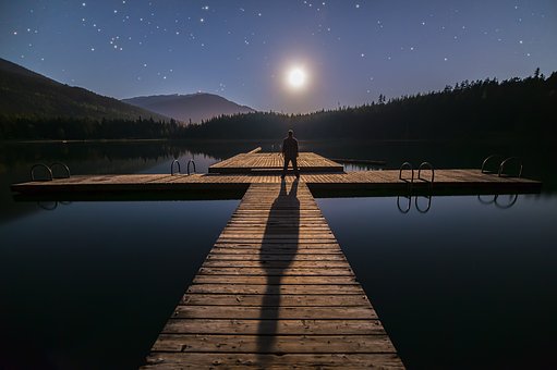 person standing on dock on lake